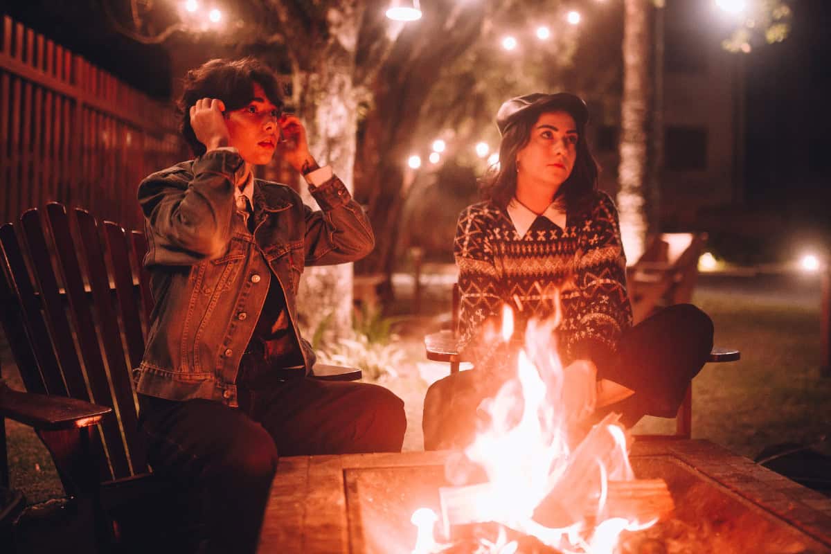 how-to-start-a-fire-pit-maintenance Image of two people around a fire pit at night.