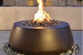 Image of a round gas fire pit on a patio for a blog post covering fire pit media.