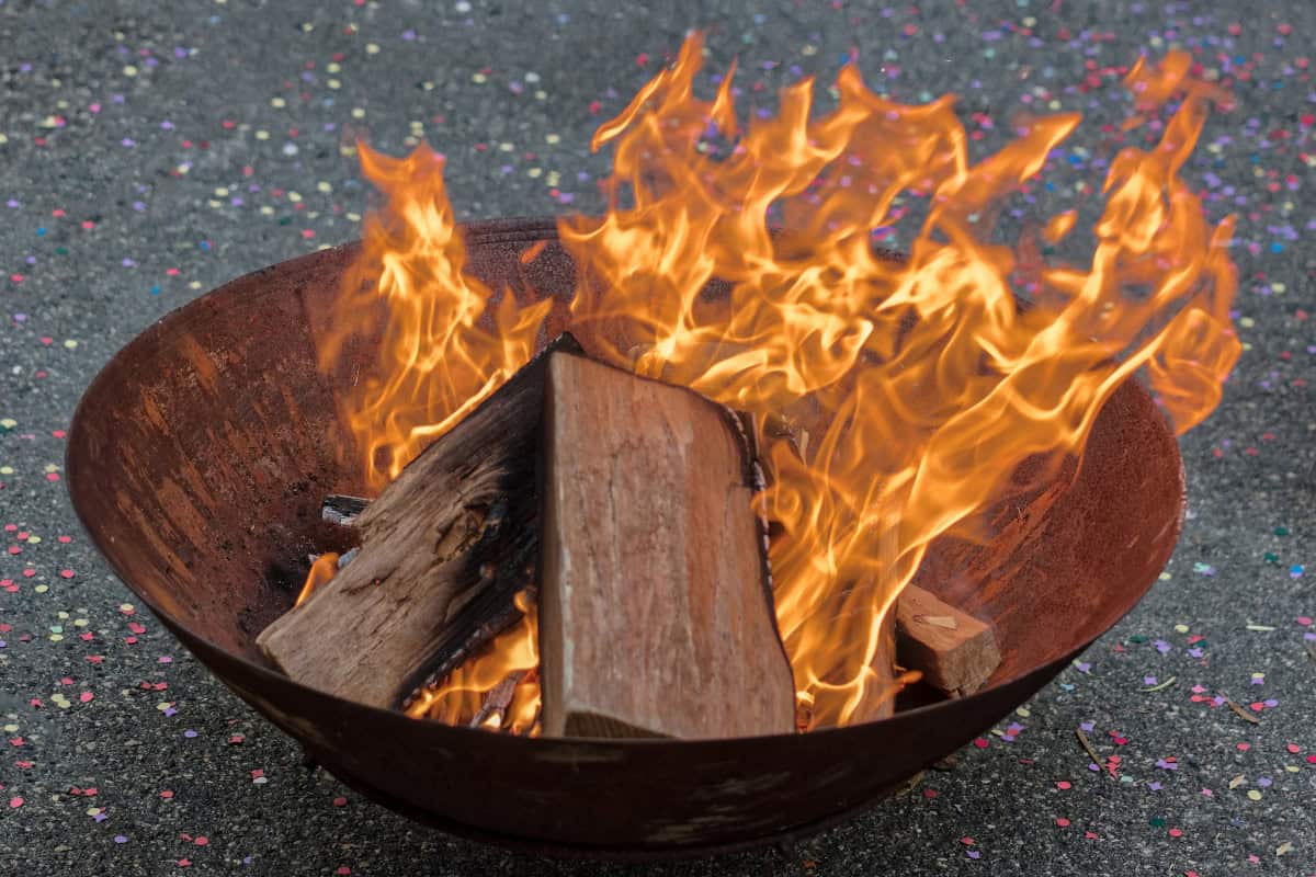 city-fire-pit-rules-placement Image of a burning fire pit bowl on asphalt for a guide covering city fire pit rules.