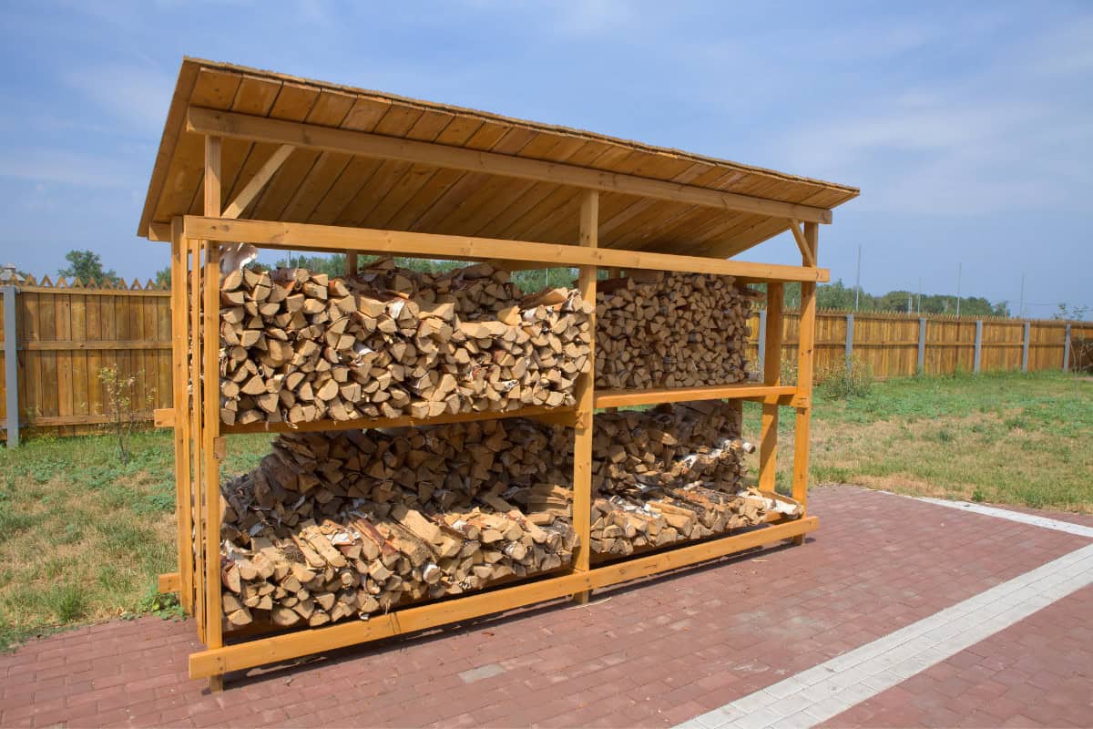 rick-of-firewood-faqs Image of split firewood in a shelter for a blog post answering the question, "what is a rick of firewood?"