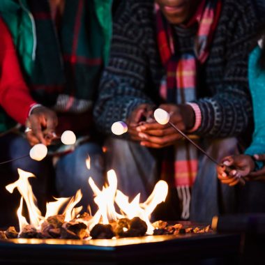 Image of a family roasting marshmallows over a gas fire pit.