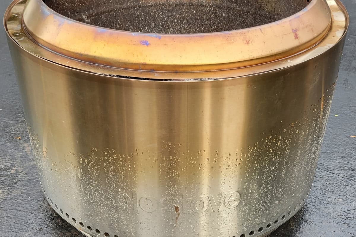 solo-stove-got-rained-on-main Stainless steel outdoor fire pit with a round, sleek design, perfect for backyard gatherings and cozy evenings. The fire bowl is filled with ashes, ready for use.