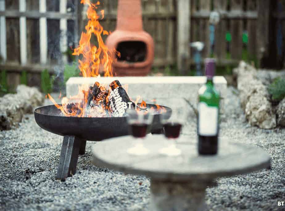 Image of a backyard fire pit burning with a bottle of wine in the foreground