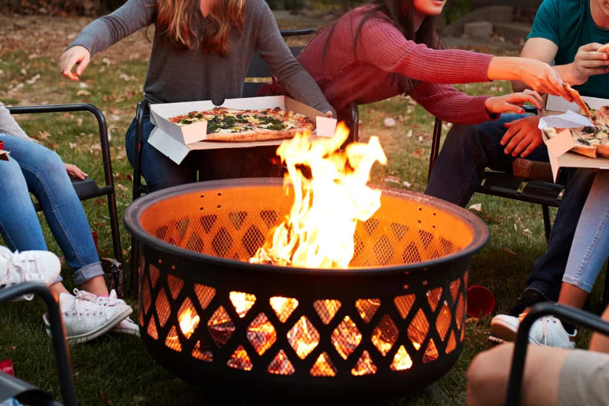 fire-pit-benefits-social-hub Image of teenagers eating pizza around a burning fire pit.