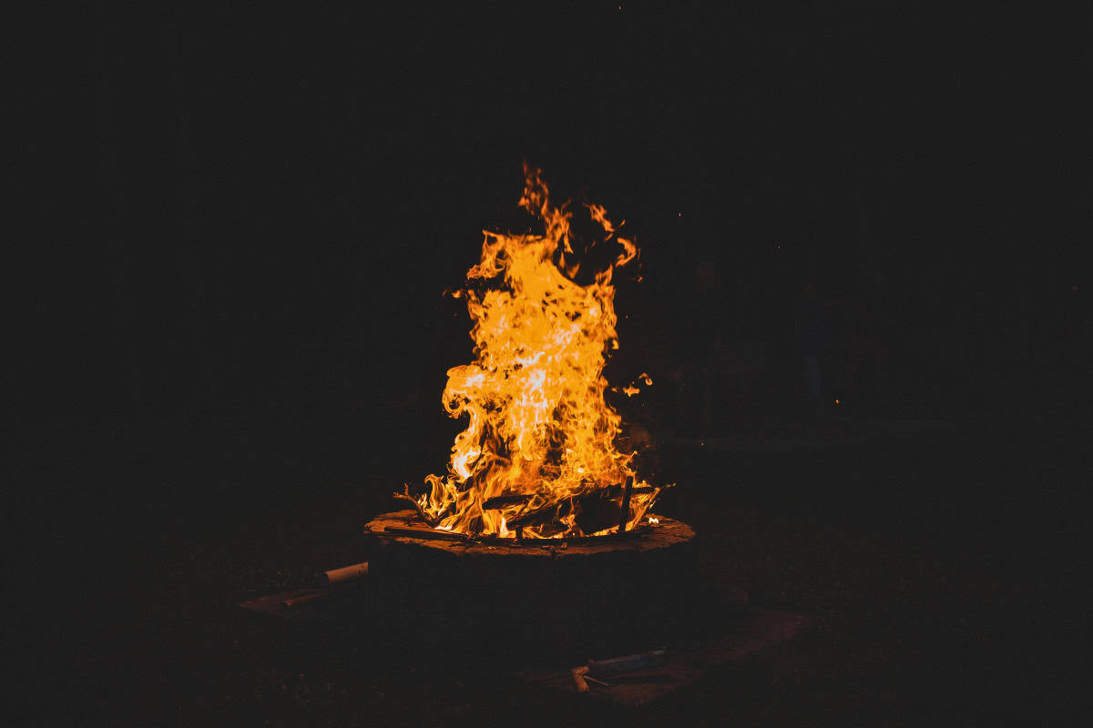 Common Mistakes to Avoid Image of a stone block fire pit burning at night for an article covering fire pit adhesives.