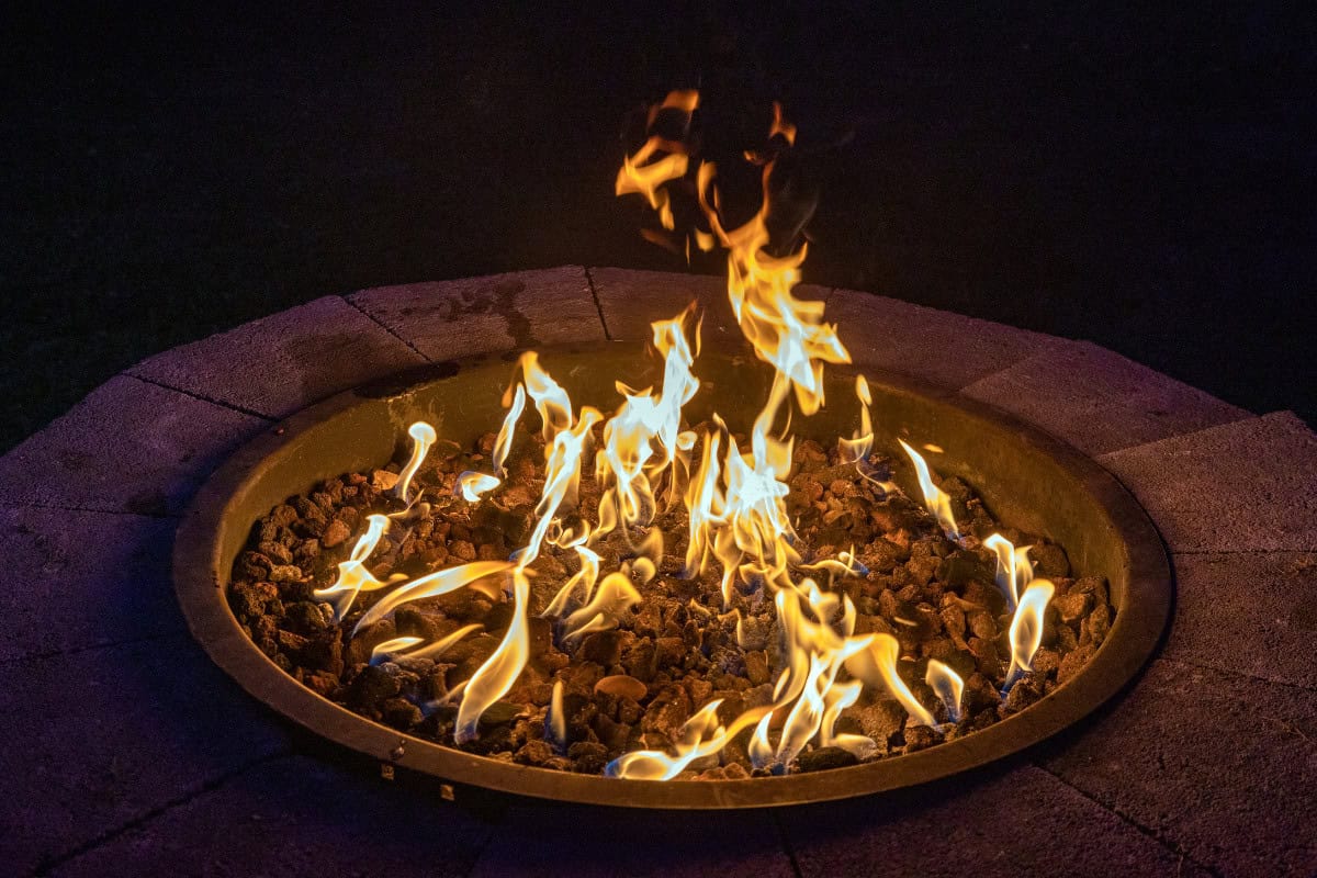 how-do-gas-fire-pits-work-closing Image of a burning gas fire pit at night for a blog post answering the question "how do gas fire pits work?"