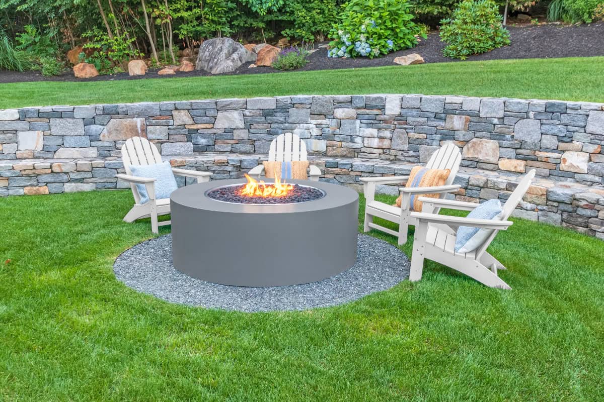 what-size-fire-pit-closing Image of a fire pit and retaining wall in a backyard for a blog post asking "what size fire pit should I buy?"