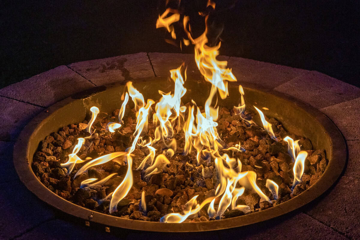 gas-fire-pits-provide-heat-maximize Image of a masonry gas fire pit burning at night.