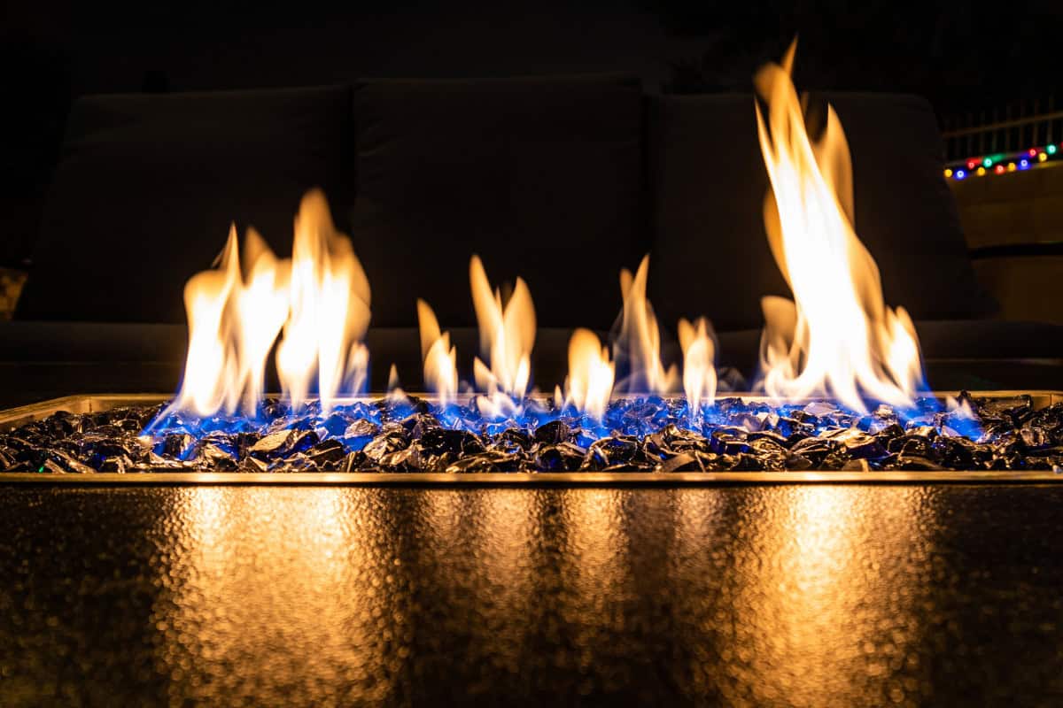 gas-fire-pits-provide-heat-safety Image of a linear gas fire pit buring at night.