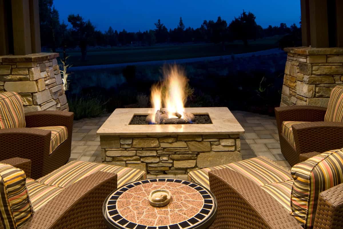 gas-fire-pits-provide-heat-understanding Image of a square gas fire pit and chairs at night.