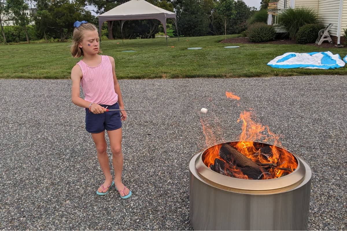 what-size-solo-stove-main Image of a young girl roasting a marshmallow over a SoloStove Yukon for a blog post answering the question "what size Solo Stove should I buy?"