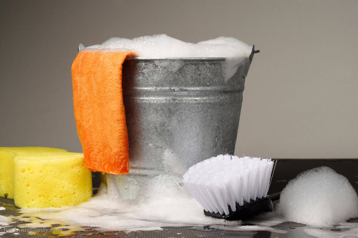 measure-for-a-fire-pit-cover-faqs Image of a bucket of soapy water, rags and brush.