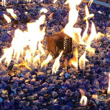 Image of a burning natural gas fire pit at night for a blog post about various fire pit fuels.