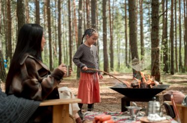 Cozy outdoor camping scene with children roasting food over an open fire in a wooded forest setting, featuring a backyard toast backyard toastymark every element for outdoor dining and camping enjoyment.