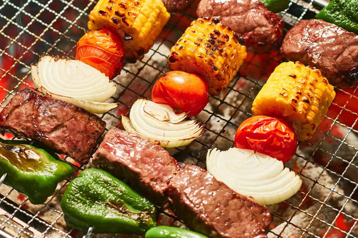 fire-pit-under-covered-patio-faqs Juicy steaks, grilled vegetables, corn on the cob, cherry tomatoes, and onions sizzling on a backyard grill for outdoor barbecue grilling.