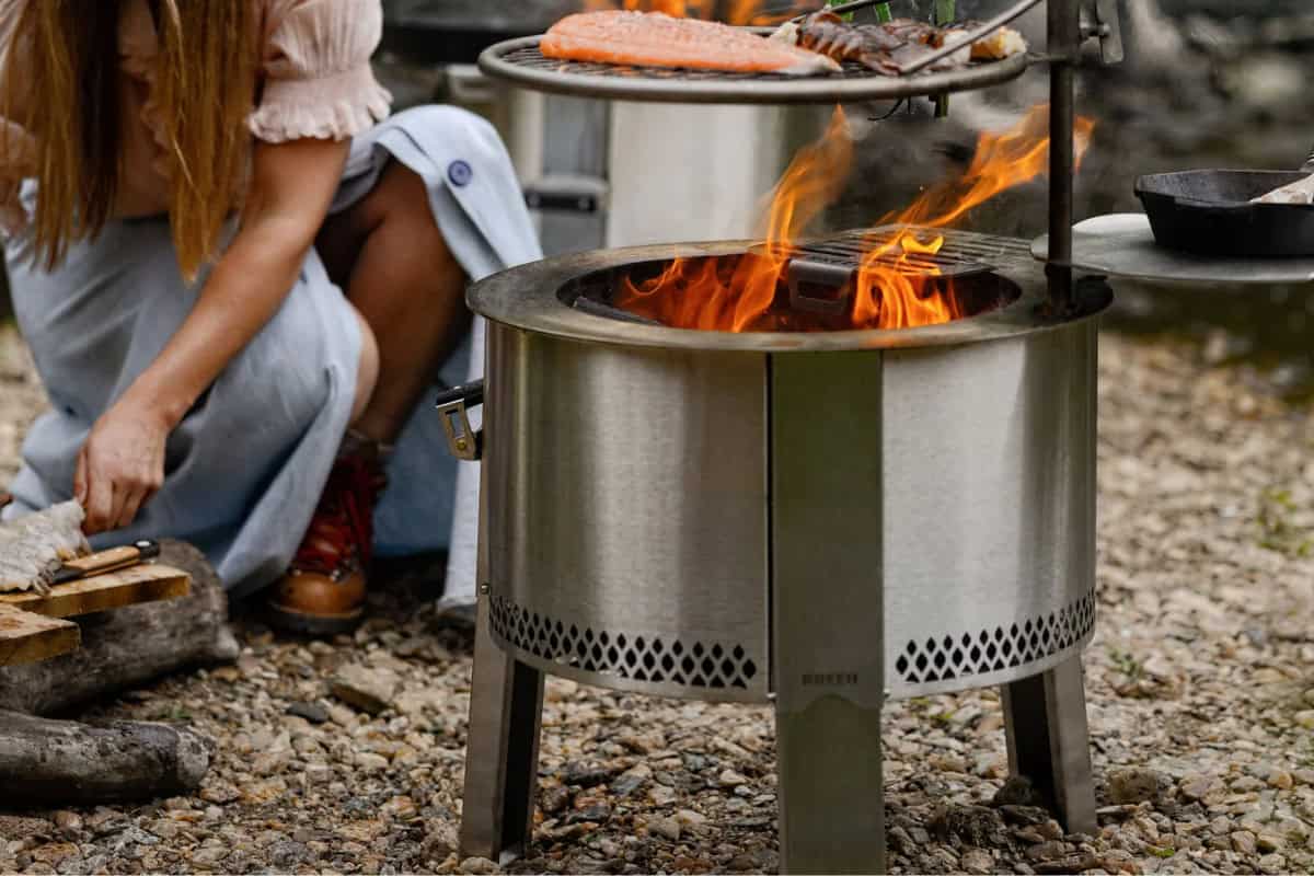 best-portable-fire-pits-closing Image of a woman grilling on a portable fire pit.