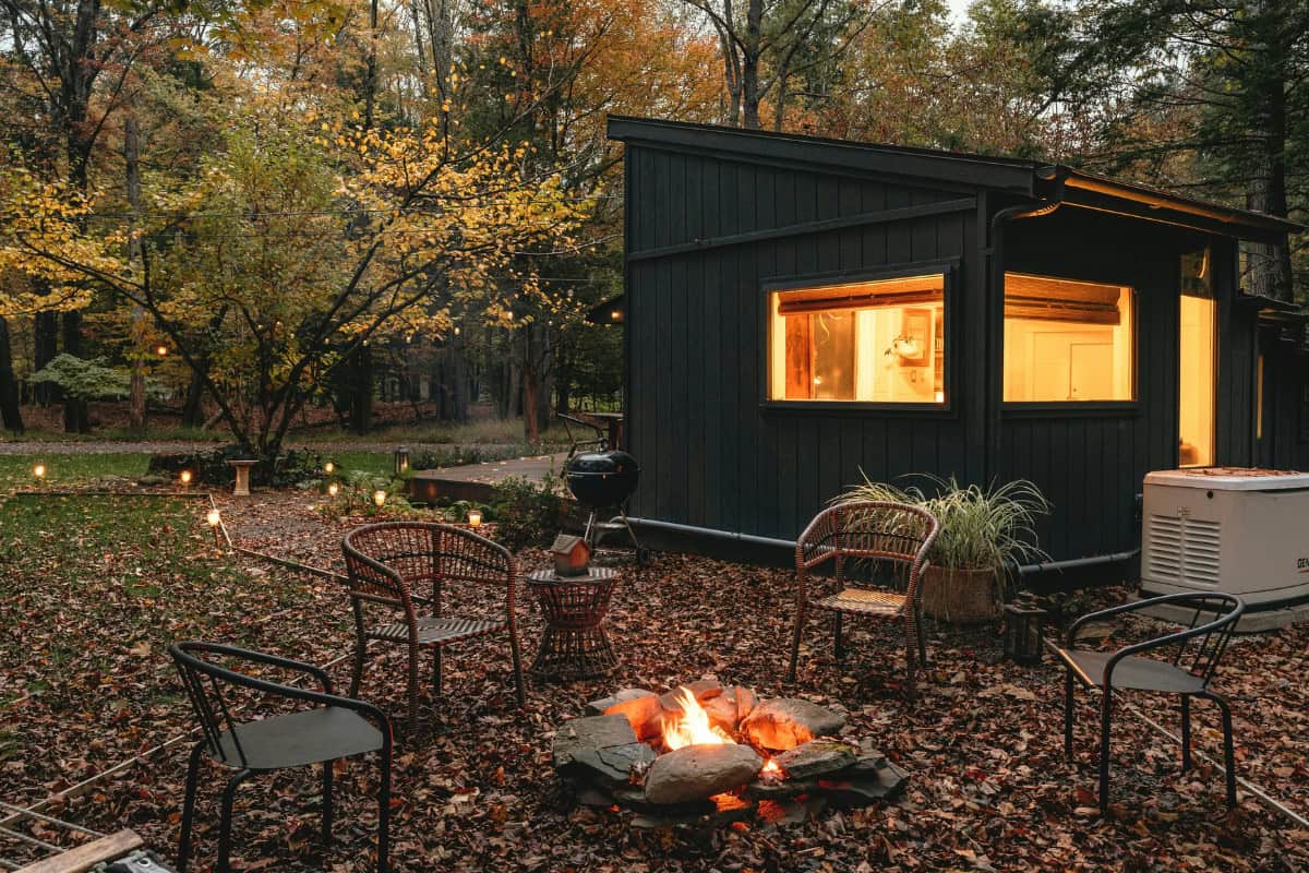 Image of a tiny home with a stone fire pit nearby.