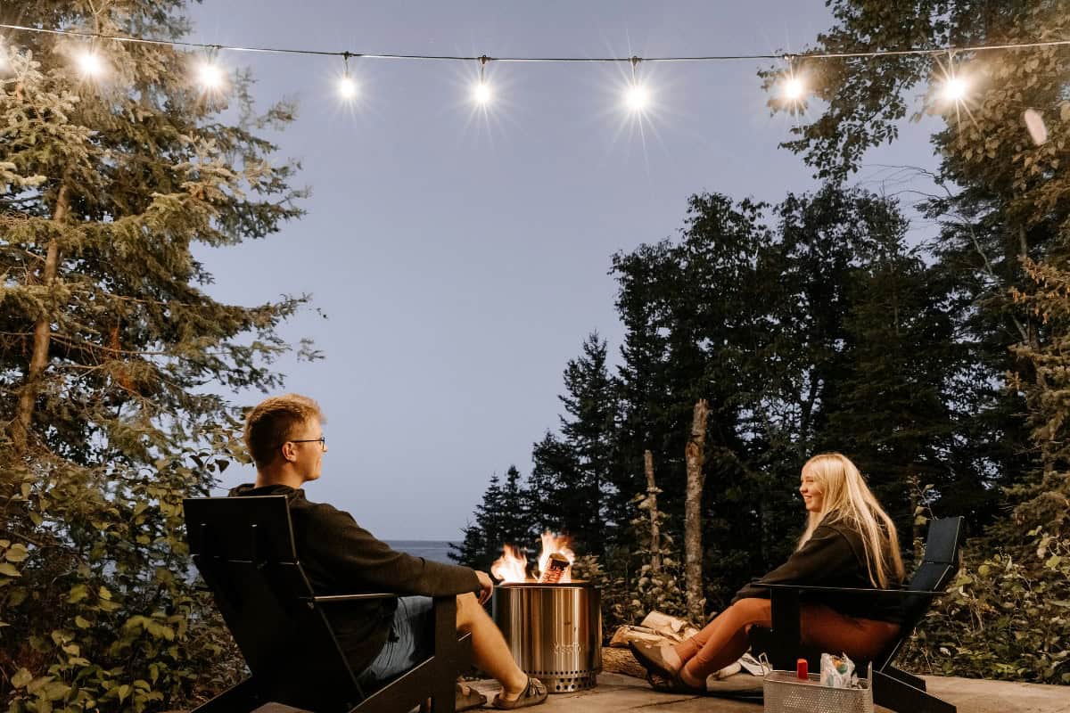 Image of a smokeless fire pit with wo people seated demonstrating compliance with fire pit clearance requirements.
