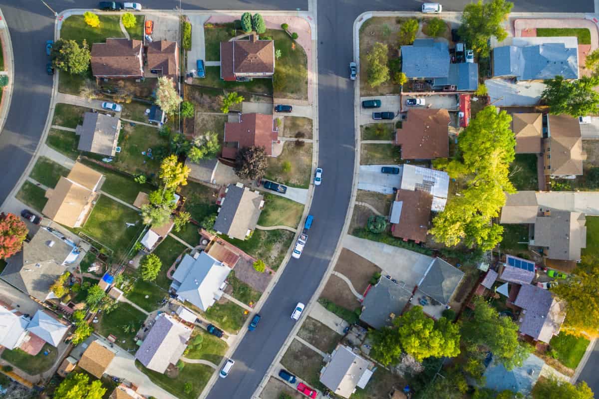 best-fire-pit-for-suburban-backyard-why Aerial view of a suburban neighborhood with houses, trees, and cars on the streets, showcasing a peaceful and well-maintained community.