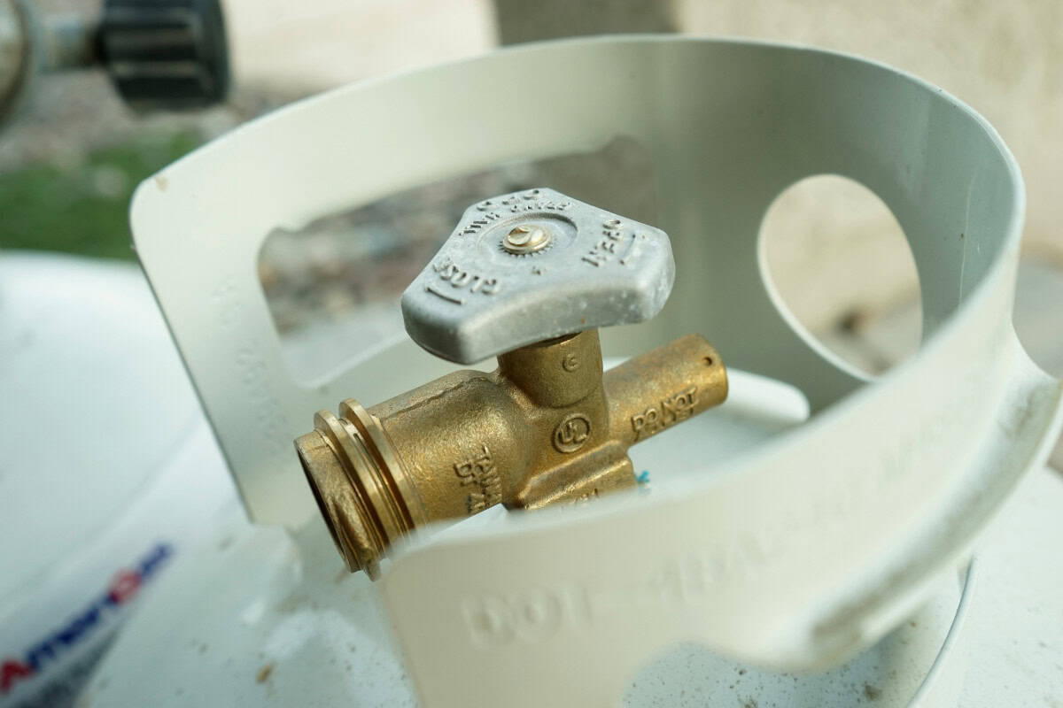 gas fire pit problems-flame-quality Bronze gas valve inside a white propane tank, ready for outdoor heating or cooking appliances at backyard parties.